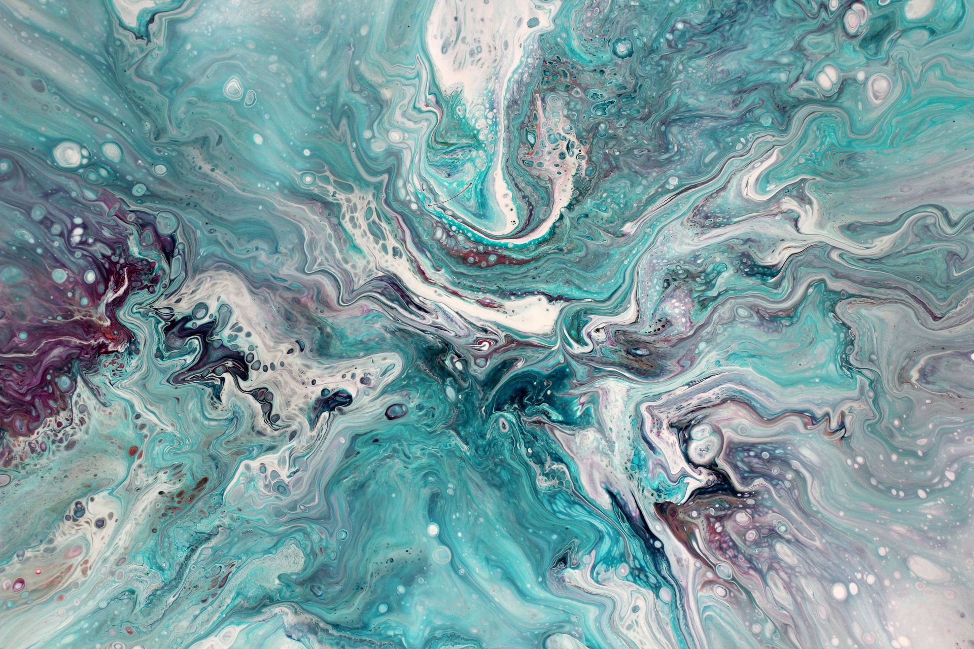 A dynamic and colorful abstract acrylic pour painting with swirling turquoise, white, and magenta hues.