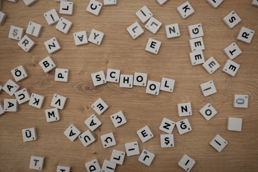 Scattered Scrabble tiles on wood with 'School' spelled out, ideal for educational themes.