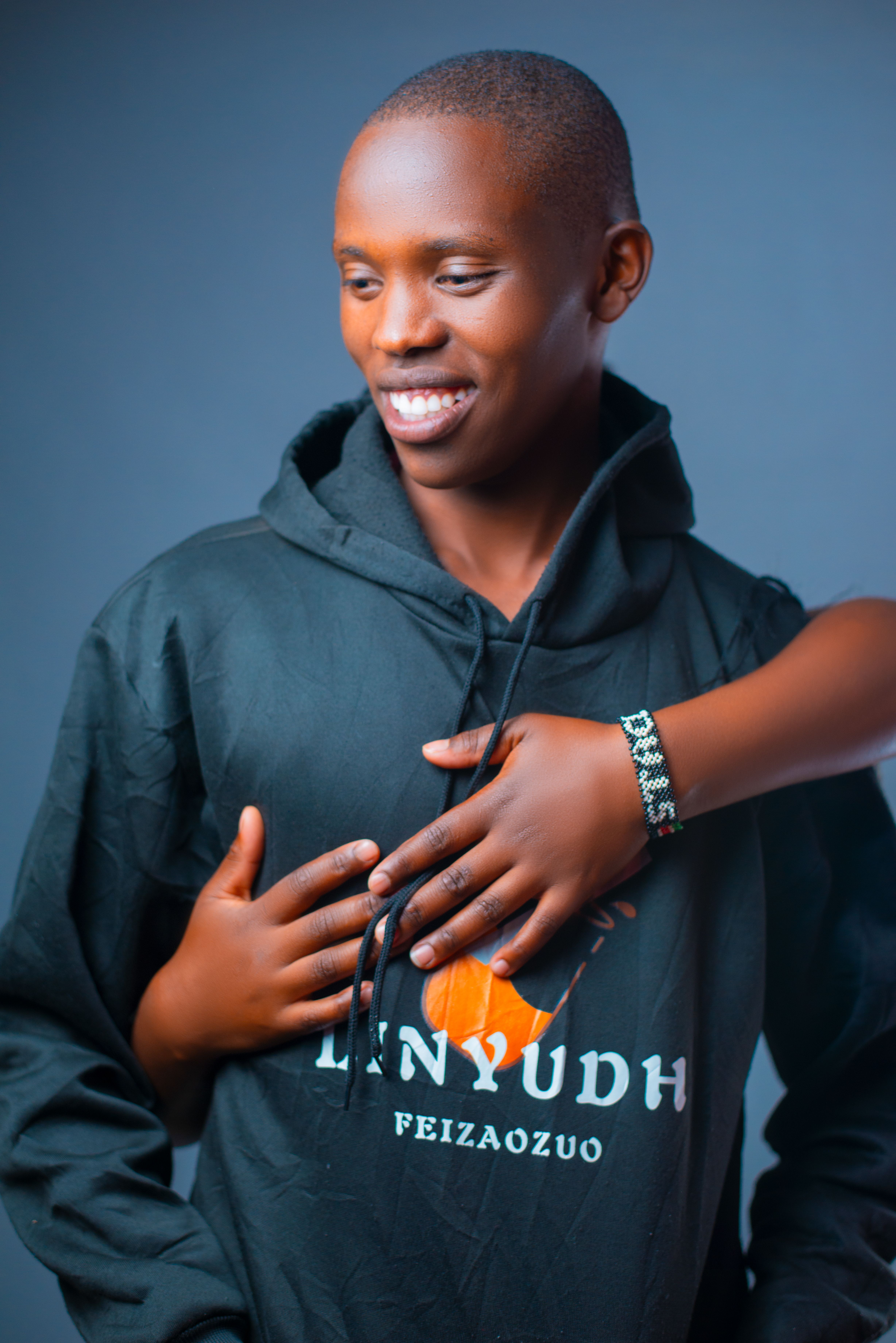 A joyful moment of friendship with a person smiling in a black hoodie, embraced by another.