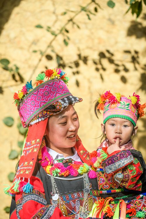 Free Mother and child wearing colorful traditional clothing outdoors, smiling in sunlight. Stock Photo