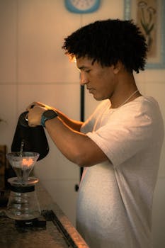 Young man preparing pour-over coffee in cozy kitchen setting.