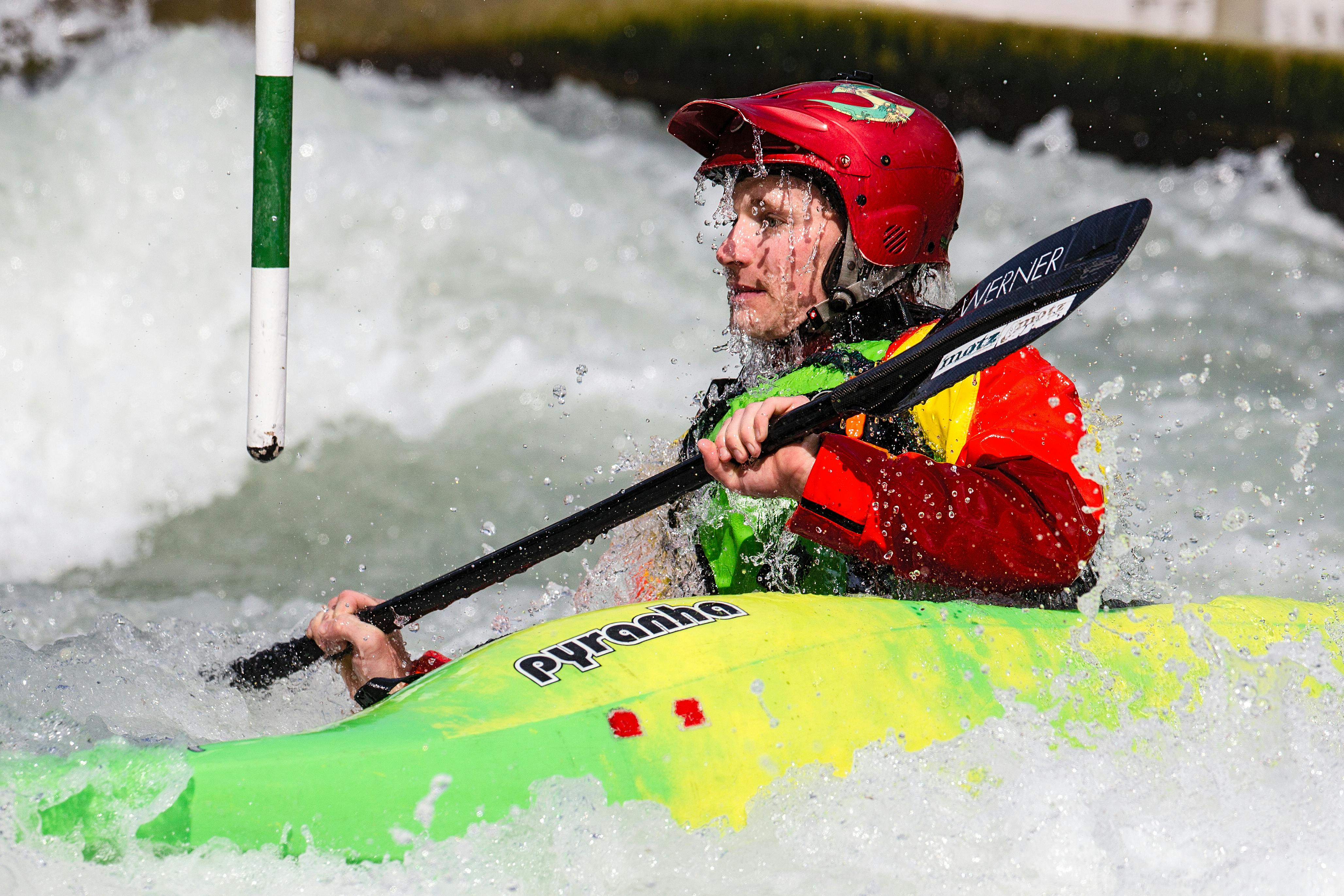 Dynamic action shot of a kayaker navigating rapids in a vibrant kayak, wearing safety gear.