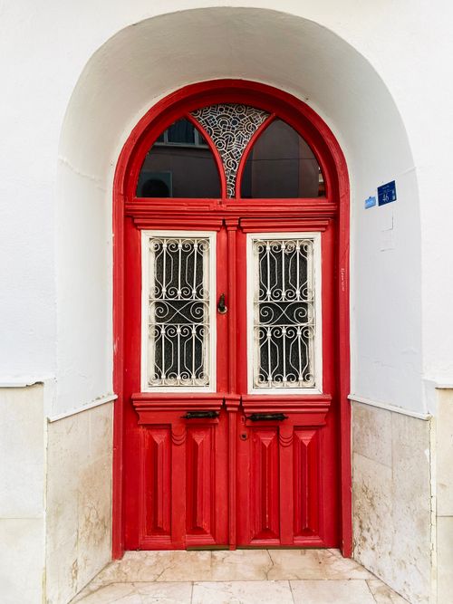 Free Elegant red arched doorway with ornate white design, perfect for architectural backdrop. Stock Photo