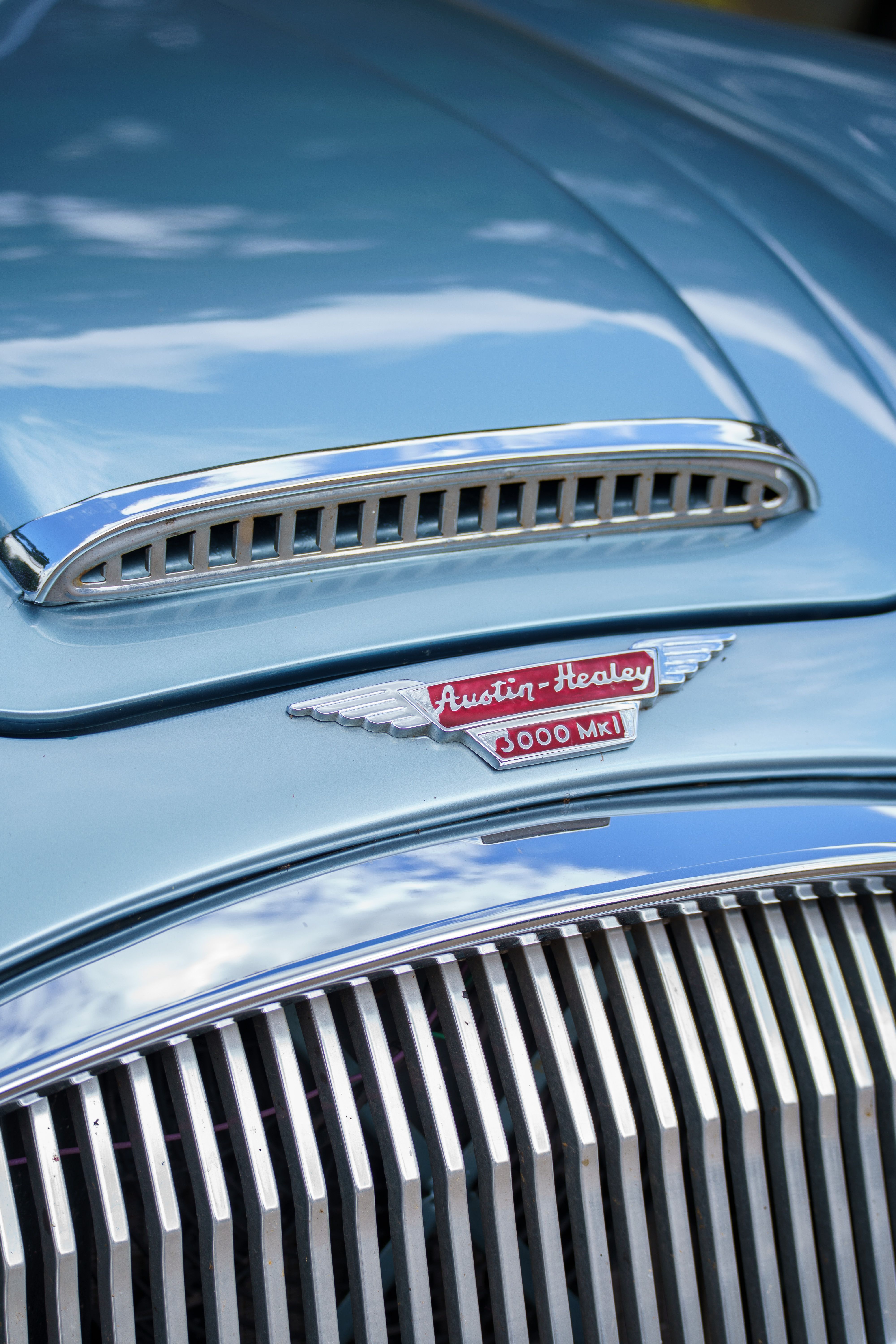 Close-up photo of the classic Austin-Healey 3000 MKI showing the emblem and grille, with a vintage aesthetic.
