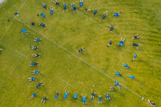 Aerial photo of a sports team practicing on a grassy field in a circular formation.