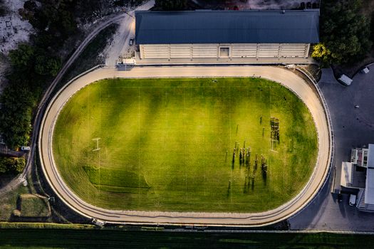 Aerial photo of a sports stadium in Budapest showing a field surrounded by a track at twilight.