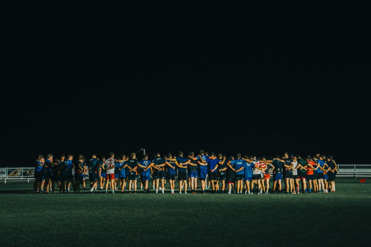 sports team huddle on a field at night fostering teamwork and unity
