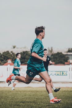 Group of young male athletes in action on a soccer field during daylight.