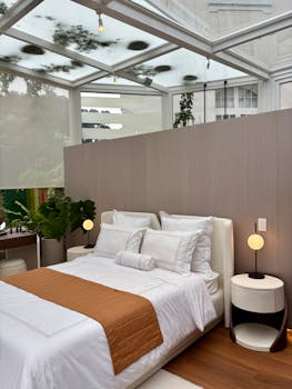 Well-decorated bedroom with glass ceiling and modern decor, featuring elegant bedding and lamps.