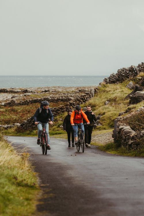 Free Cyclists enjoy a ride on the picturesque roads of Inishmore, Ireland, near the Atlantic coast. Stock Photo