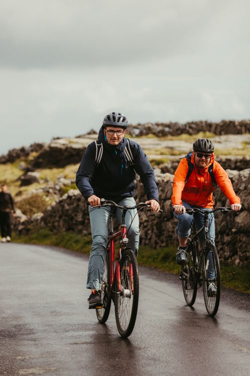 Free Two cyclists ride along a picturesque road in Inishmore, Ireland. Stock Photo