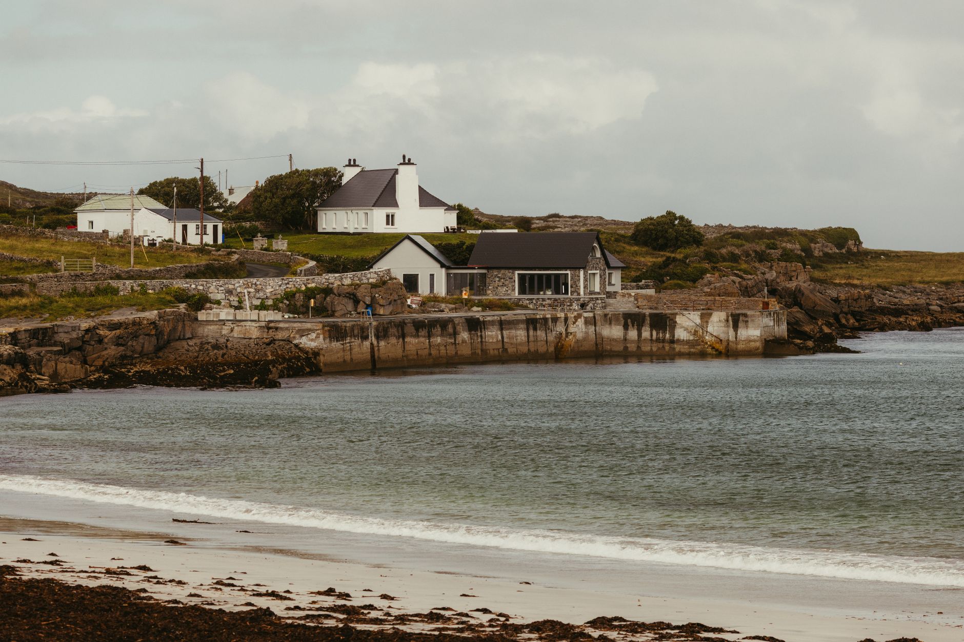Charming coastal homes along a serene beach on Inishmore in County Galway, Ireland.
