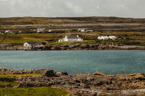 Free Picturesque coastal scene of Inishmore, County Galway, Ireland with traditional houses and rocky shoreline. Stock Photo