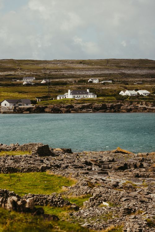 Free Explore the rugged beauty of Inishmore's coastline, featuring traditional stone houses and turquoise waters. Stock Photo
