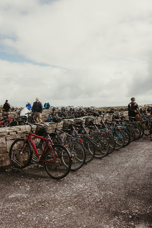 Free A line of bicycles parked against a stone wall on Inishmore, Ireland, under cloudy skies. Stock Photo