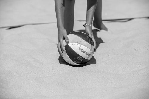 Free Close-up of a volleyball being placed on the beach sand in black and white. Stock Photo