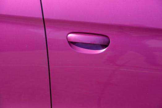Close-up photograph of a vibrant pink car door handle, showcasing modern car design.