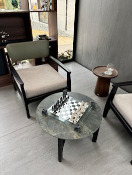 Stylish indoor lounge with a glass chessboard set on a marble table, perfect for a casual game.