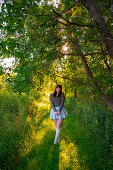 A woman poses elegantly in a Wisconsin forest during early fall, showcasing autumn fashion.