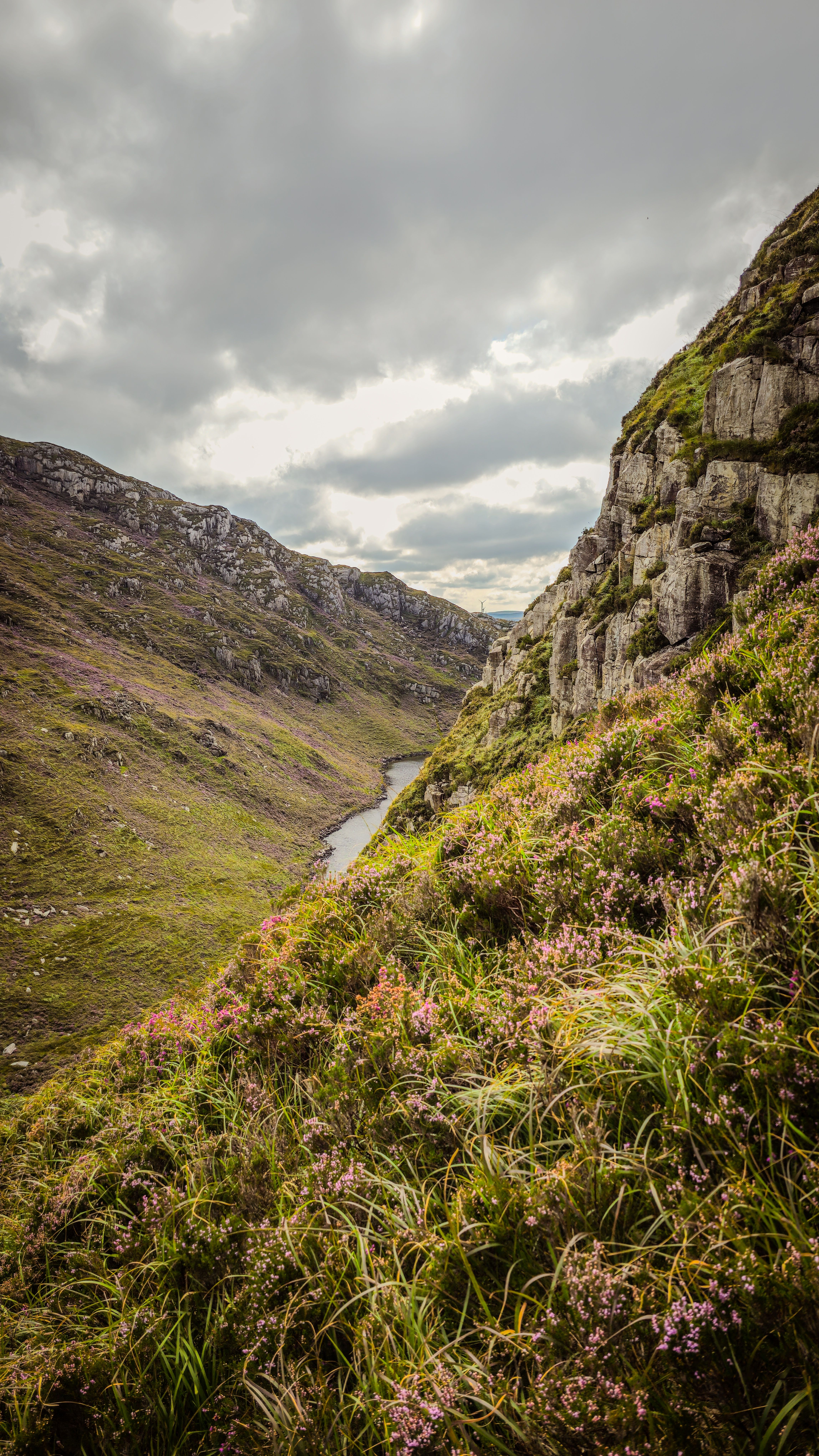 Beautiful landscape of a lush valley with rolling hills and cloudy sky in Croaghaun, Ireland.