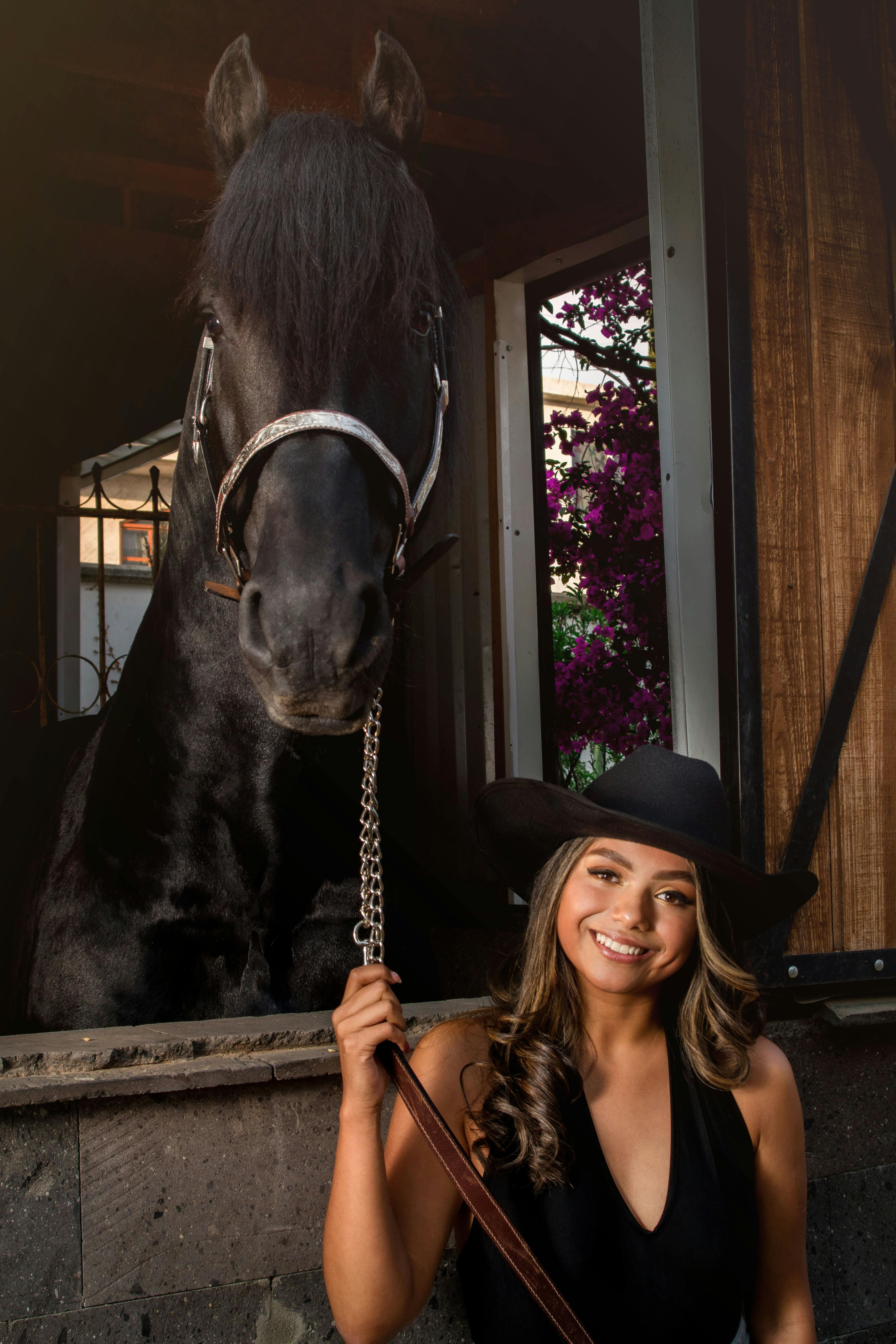 Gratis Una donna sorridente con un cappello nero posa con un cavallo nero in una stalla, Tlaxcala, Messico. Foto a disposizione