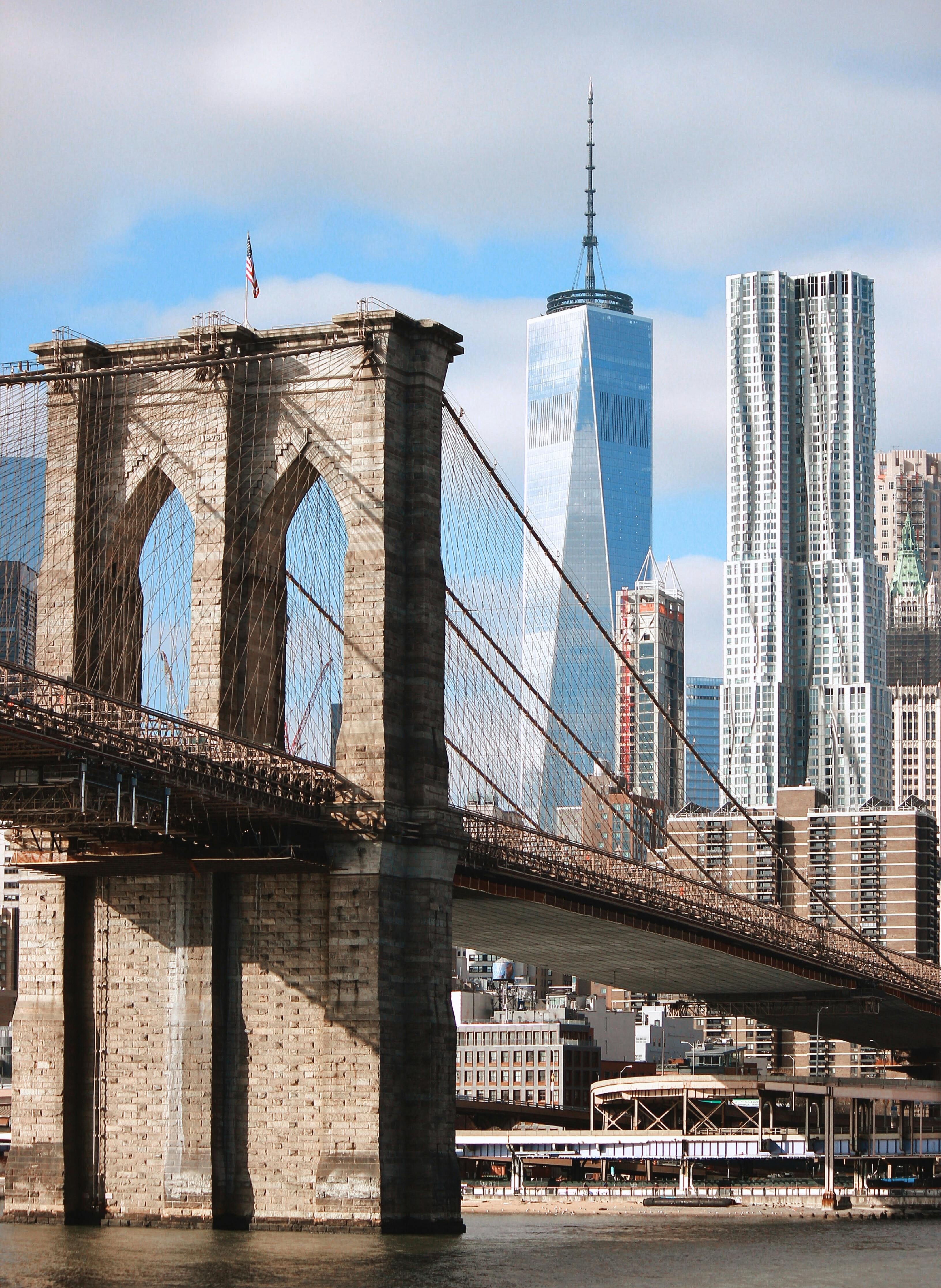 Iconic view of Brooklyn Bridge with One World Trade Center and NYC skyline in the background.