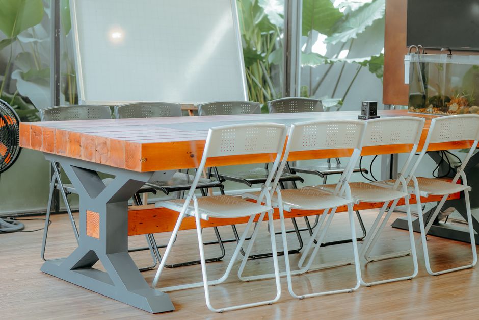 Spacious office meeting room with wooden table and white chairs. Bright and modern.