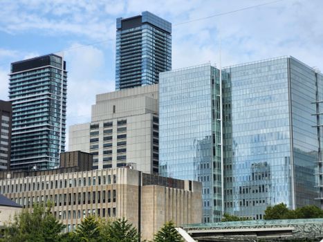 A vibrant cityscape of modern skyscrapers towering in downtown Toronto under a bright sky.