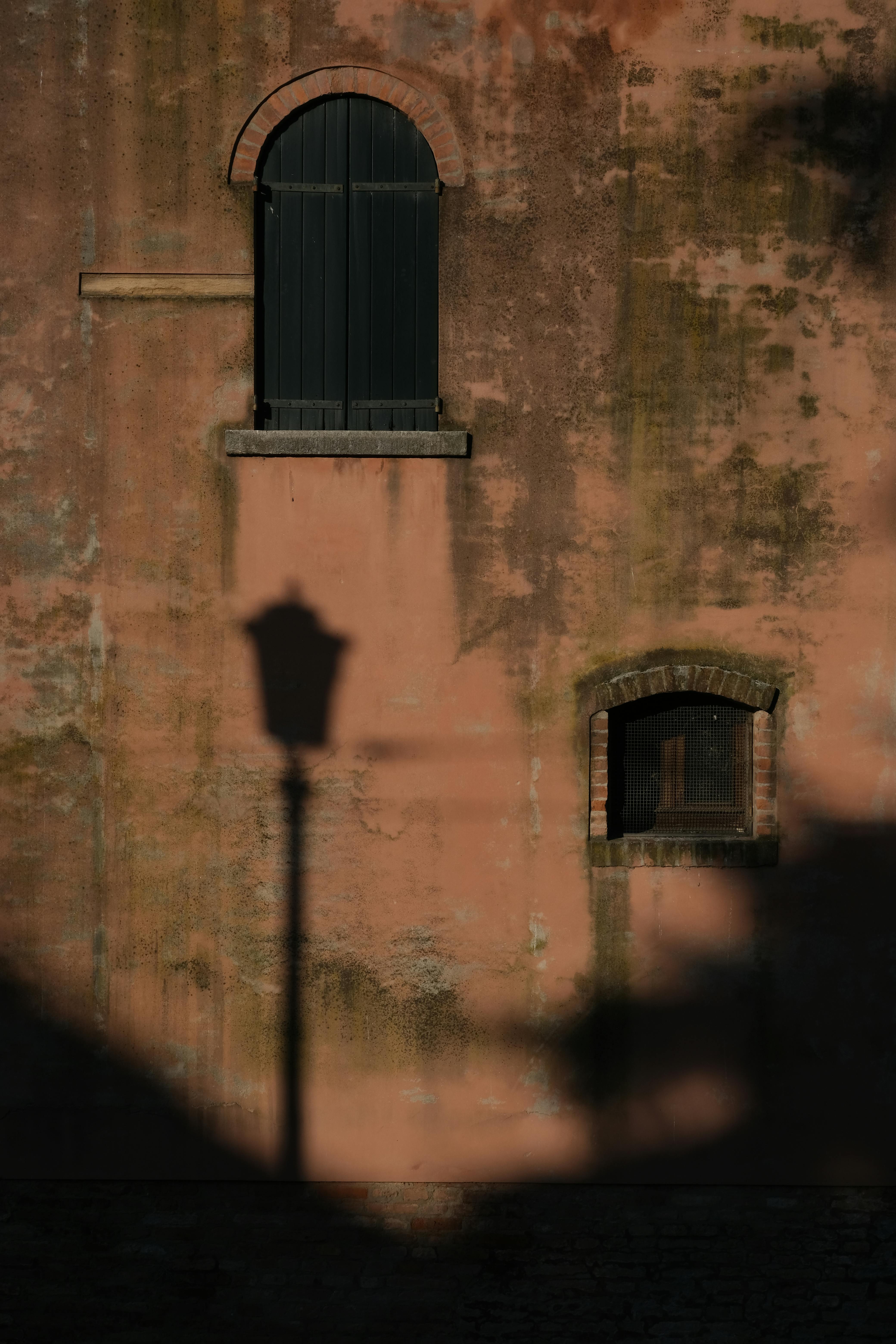Artistic shadow of streetlamp on rustic wall creates a moody sunset scene.