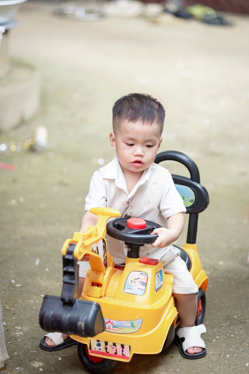 Toddler playing with a yellow toy excavator outdoors