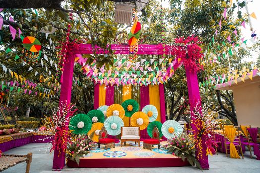 Colorful outdoor festive setup with drapes and vibrant decorations amidst lush greenery.