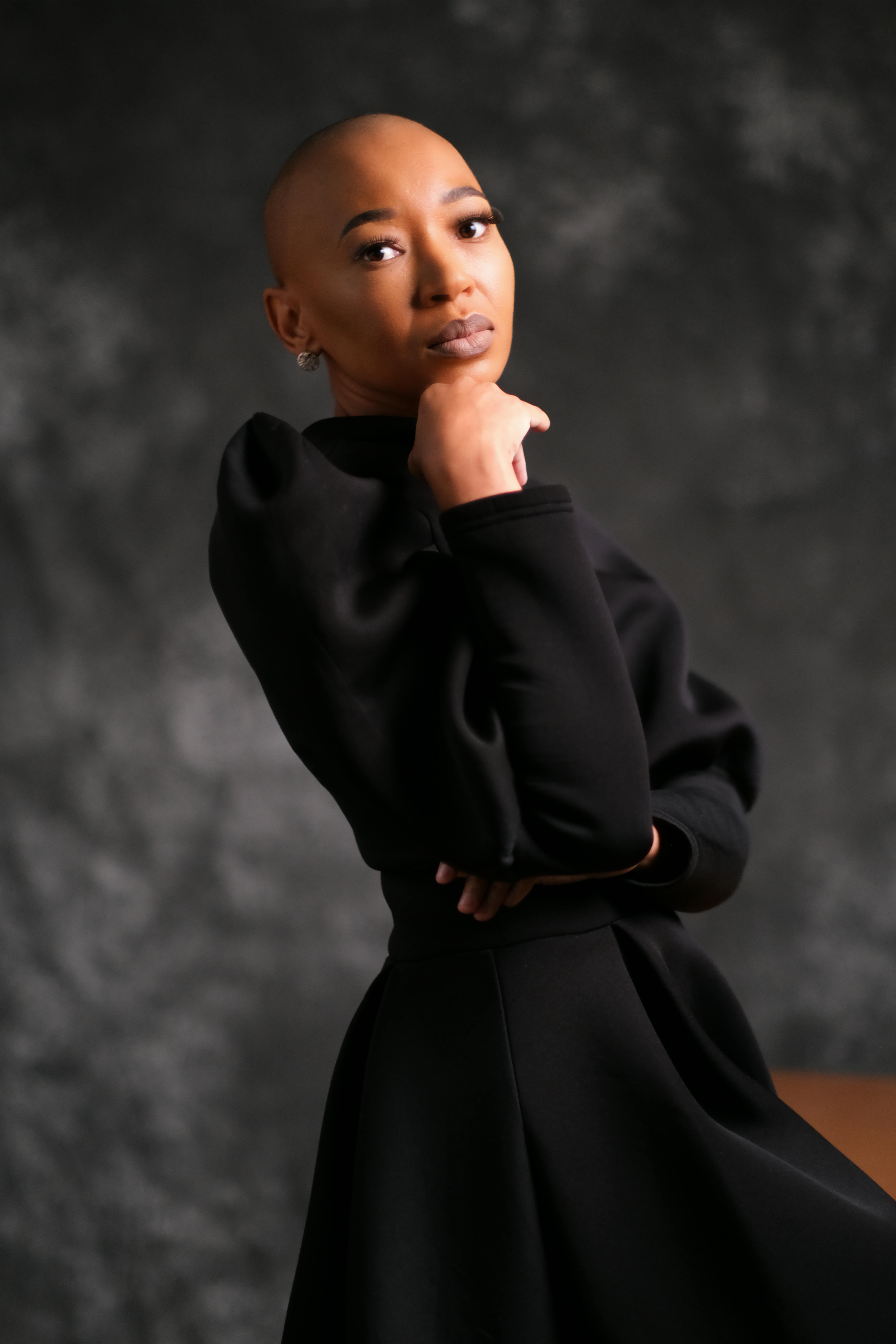 A striking portrait of a confident woman in a dark dress posing thoughtfully.