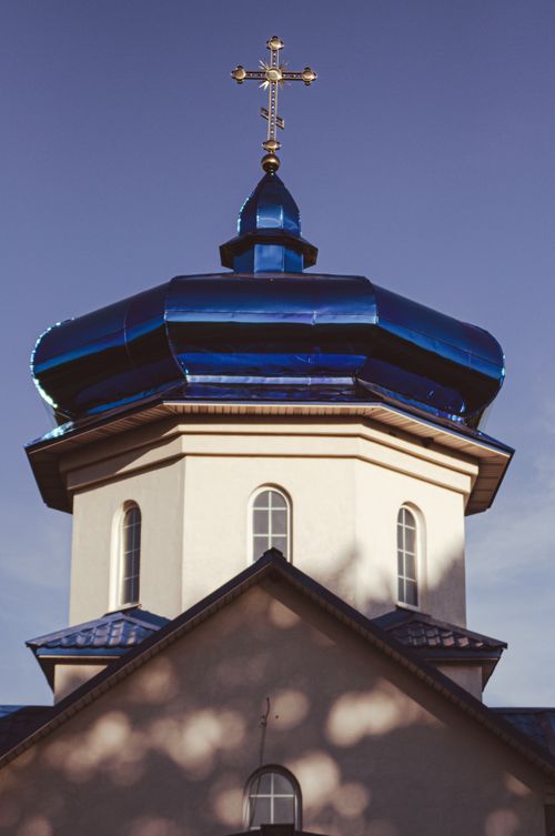 Free Elegant Orthodox church featuring a striking blue dome and cross under clear skies. Stock Photo