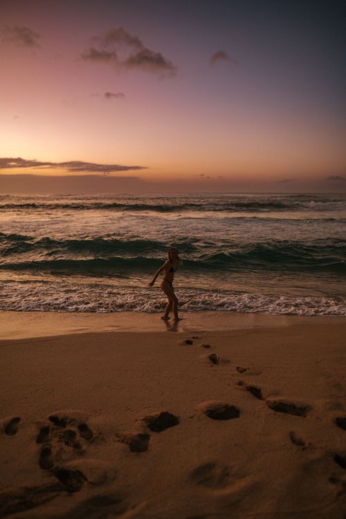 Free Serene scene of a person running by the ocean during sunset, leaving footprints on the sandy beach. Stock Photo