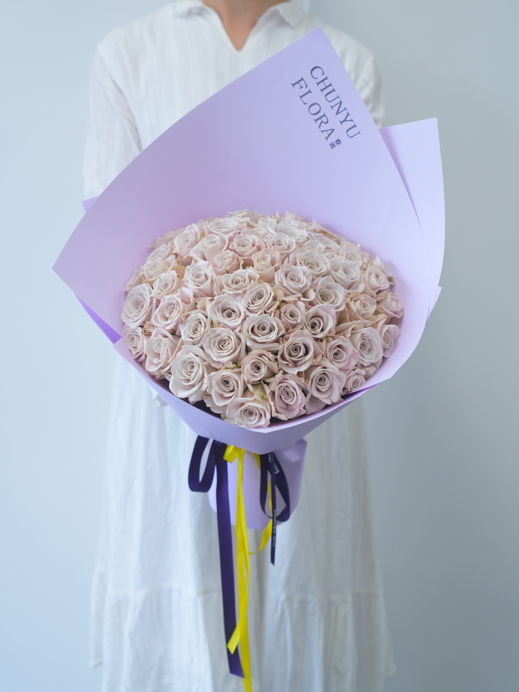 Beautiful lilac wrapped bouquet of pink roses, perfect for weddings or special occasions.
