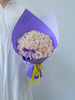 Chic bouquet of pink roses wrapped in vibrant purple, ideal for celebrations.