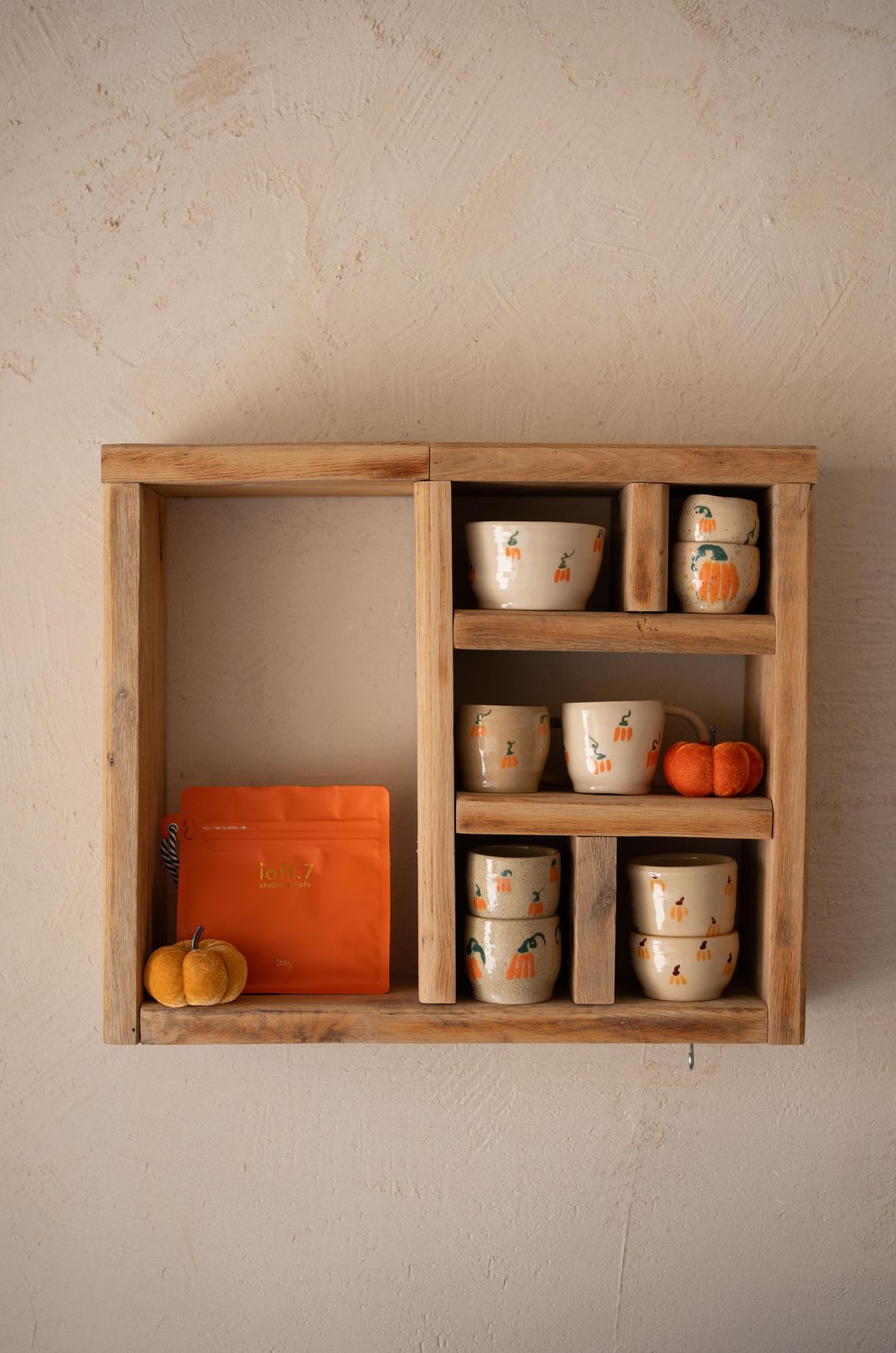 Wooden shelf displaying ceramic cups and mini pumpkins, evoking an autumnal feel. Stock Photo.