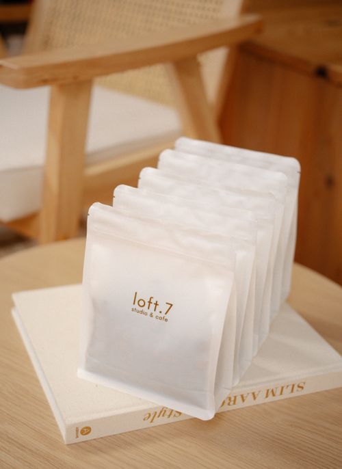 Free Elegant modern coffee packaging arranged on a wooden table with a cozy chair. Stock Photo