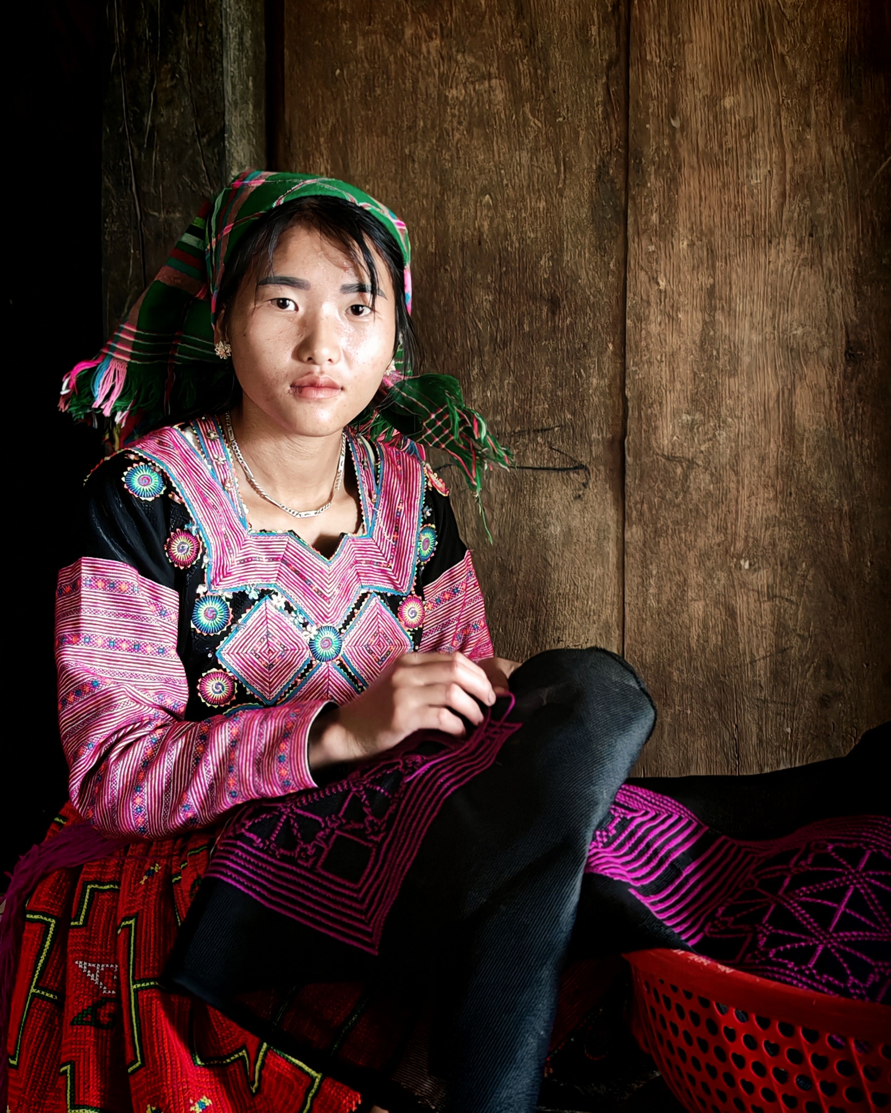Young woman in traditional ethnic dress engaged in embroidery — the living craft behind the Chinese shoulder bag's textile heritage