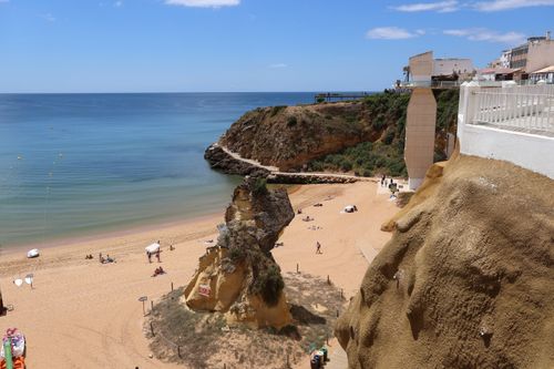 Free Beautiful beach with cliffs overlooking the calm sea under a clear blue sky. Stock Photo