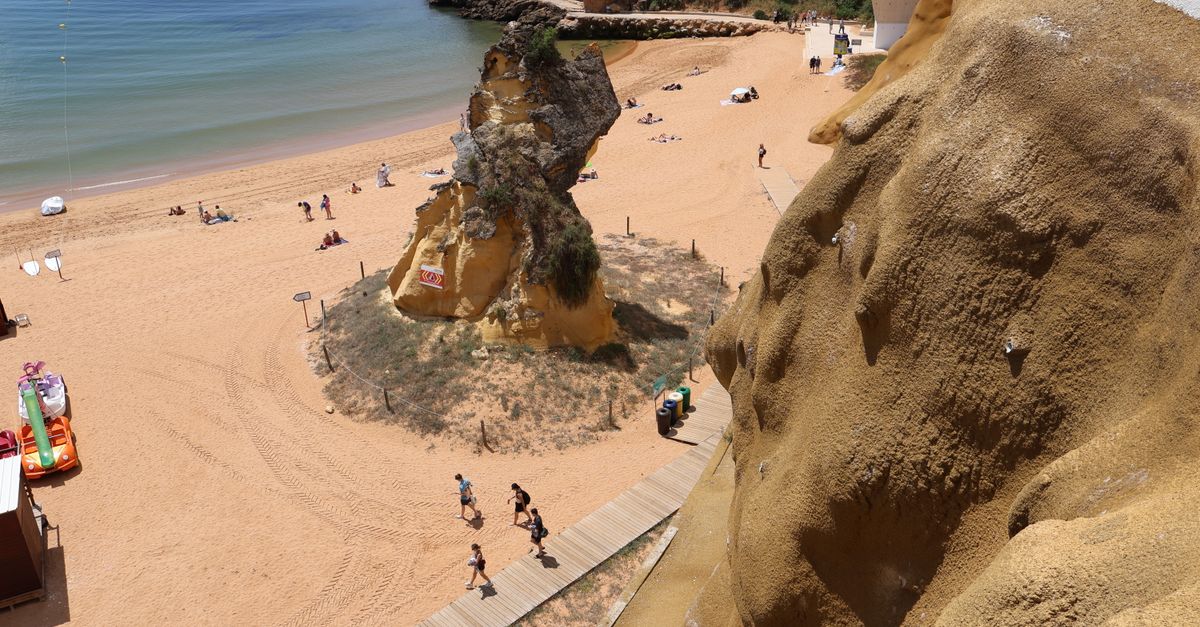 An Algarve beach with sandstone stacks and people on the sand
