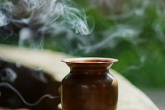 A copper pot with incense smoke creating a serene outdoor ambiance in natural sunlight.