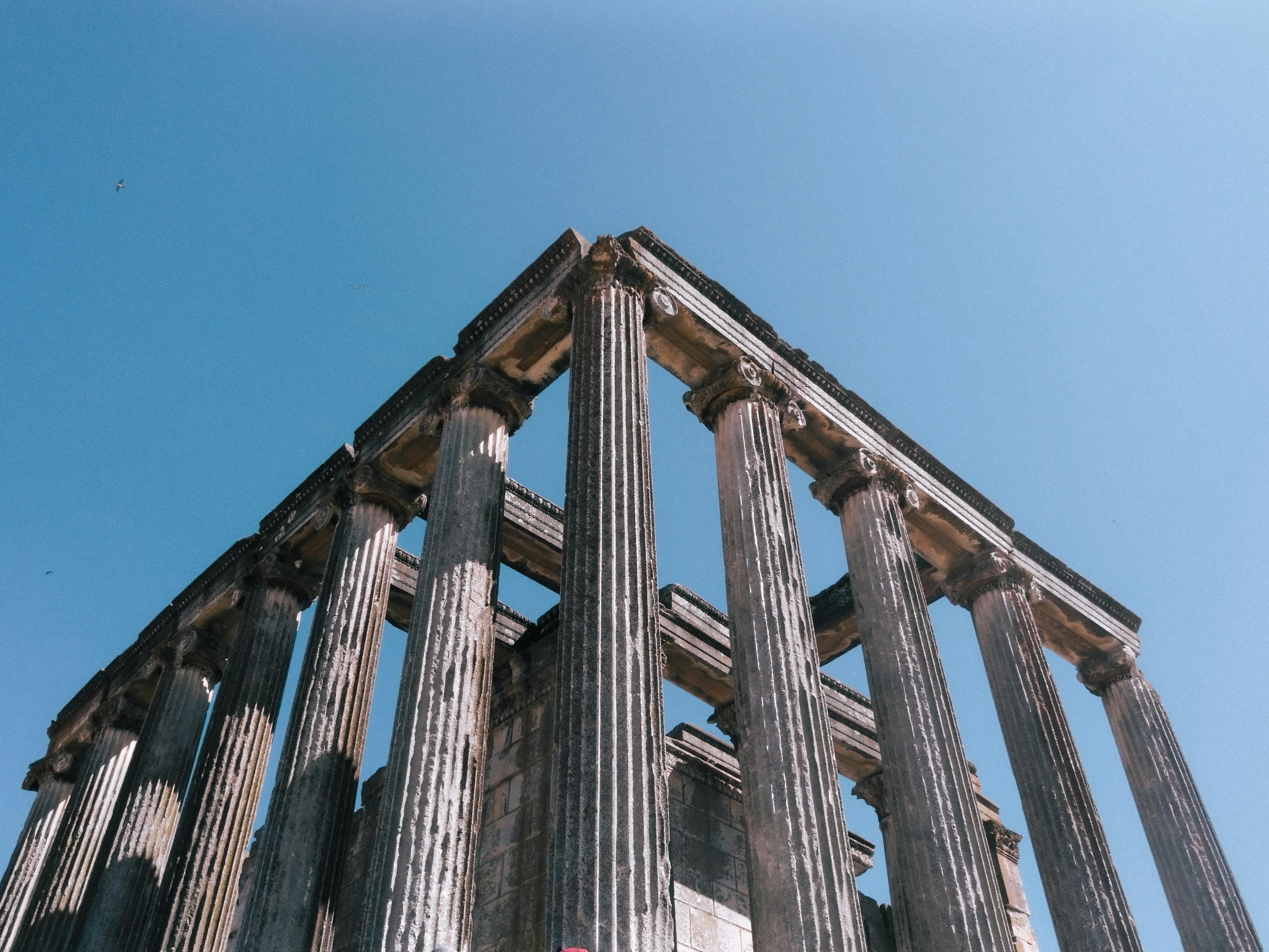 Historic Roman temple columns against a bright blue sky, showcasing ancient architecture.