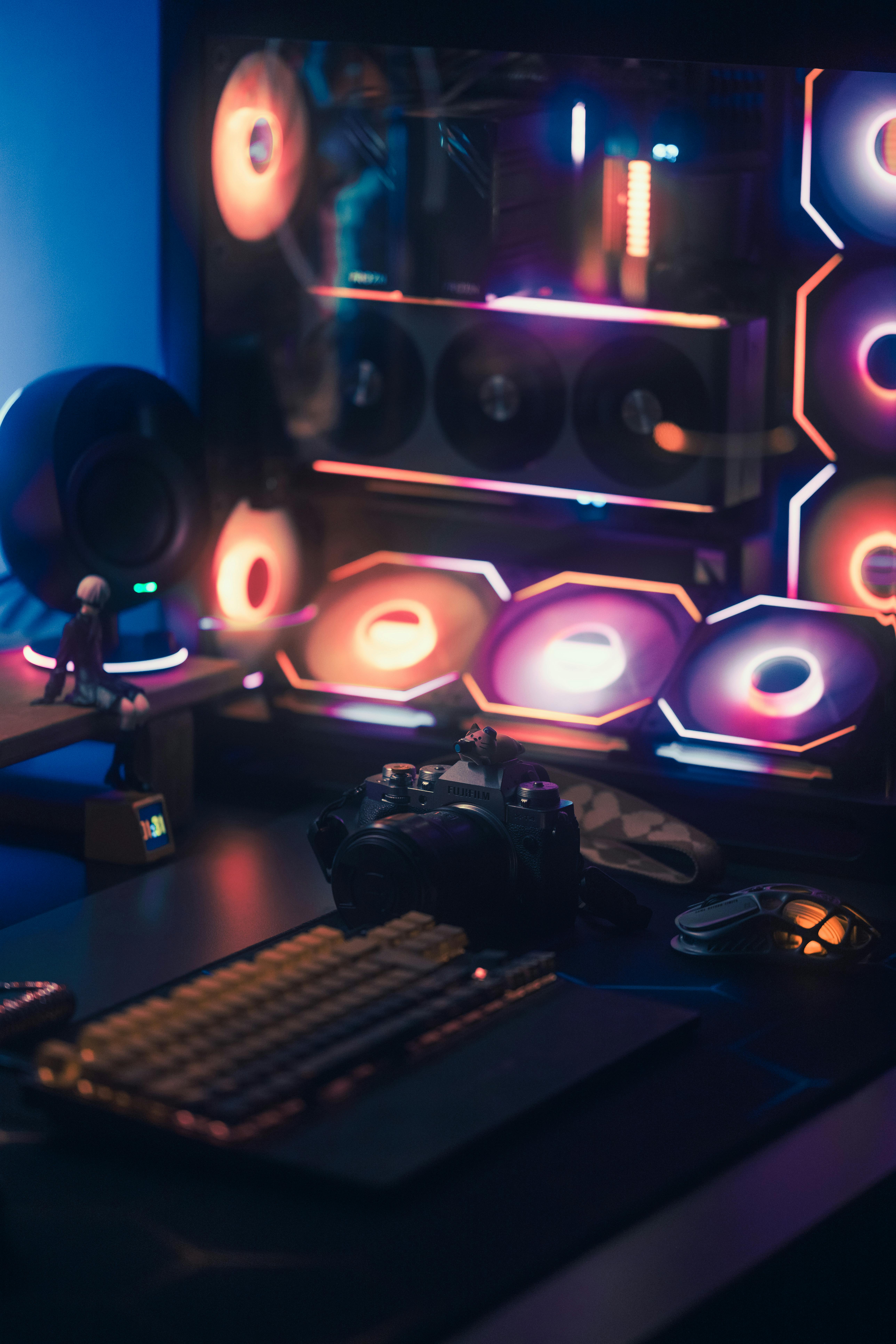 A stylish gaming setup featuring RGB lighting, keyboard, and a camera against a vibrant backdrop.