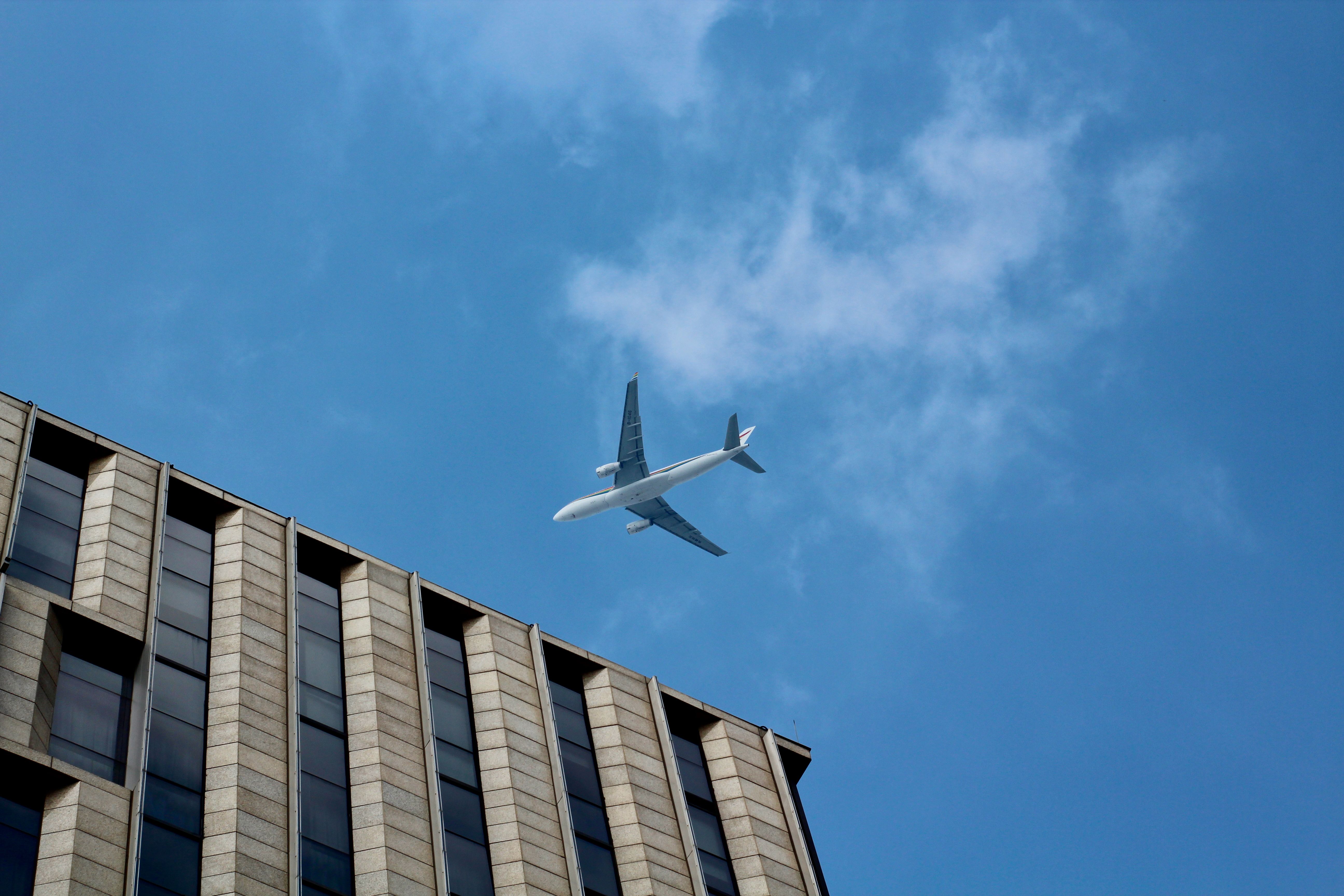 Airplane Near Blue and Grey Building · Free Stock Photo