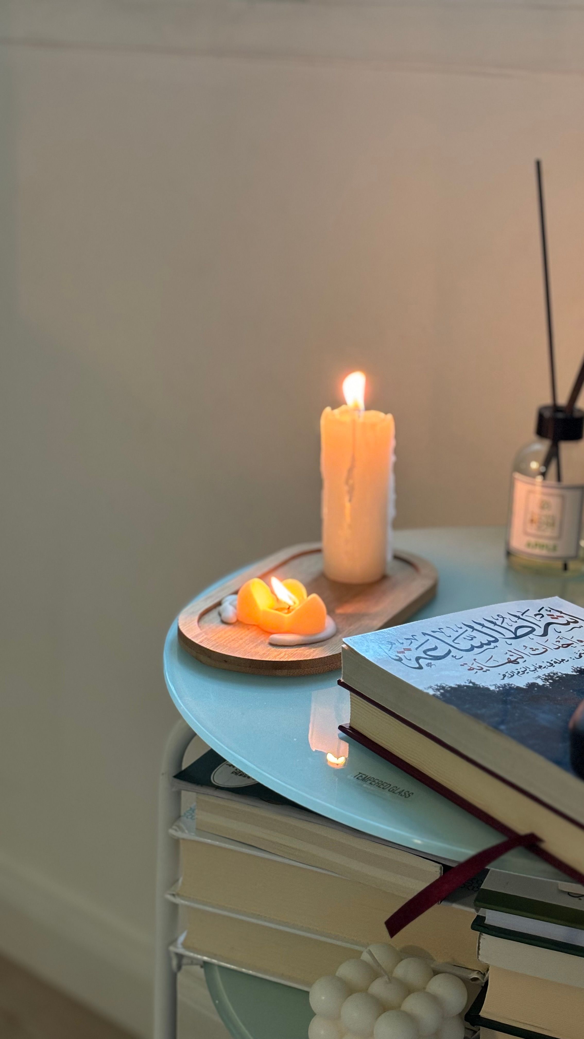 A serene indoor scene featuring a candle, books, and a calming atmosphere, ideal for relaxation.