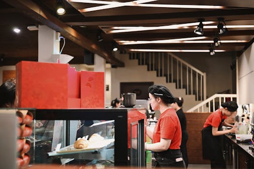 Baristas wearing red uniforms working in a bustling café, preparing beverages.