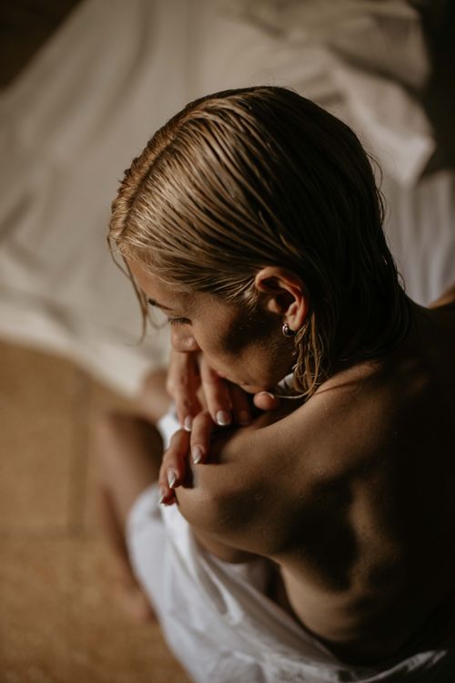 Free A reflective moment capturing a woman with wet hair, wrapped in a towel, in soft natural lighting. Stock Photo