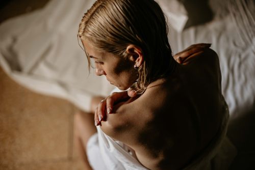 Free A woman with wet hair wrapped in a towel, captured in a serene, intimate indoor setting. Stock Photo