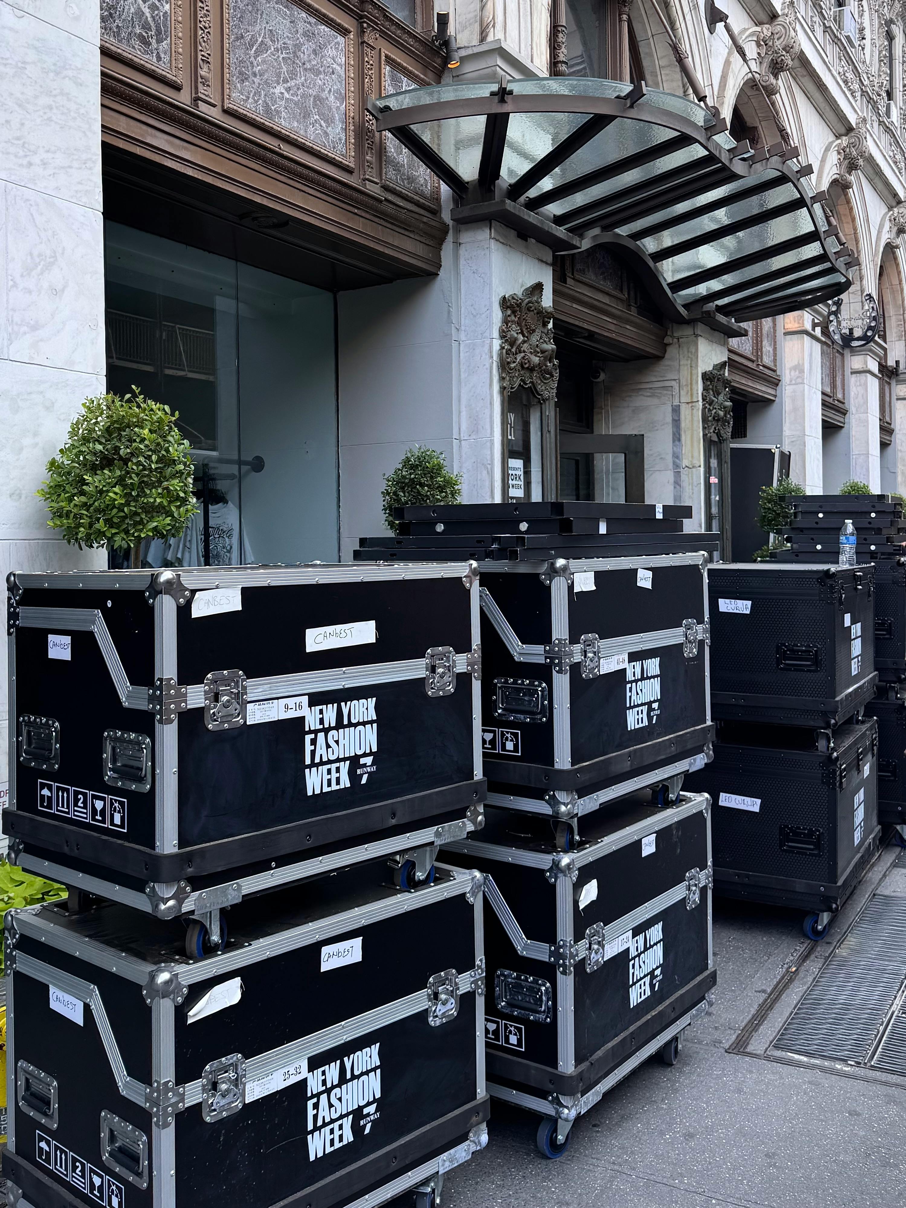 Stacked equipment cases on display outside a building for New York Fashion Week.